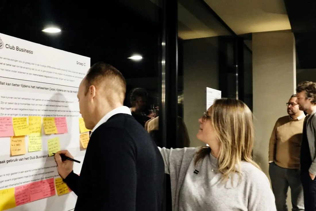Een lid kleeft post-its op een groot bord tijdens de workshop